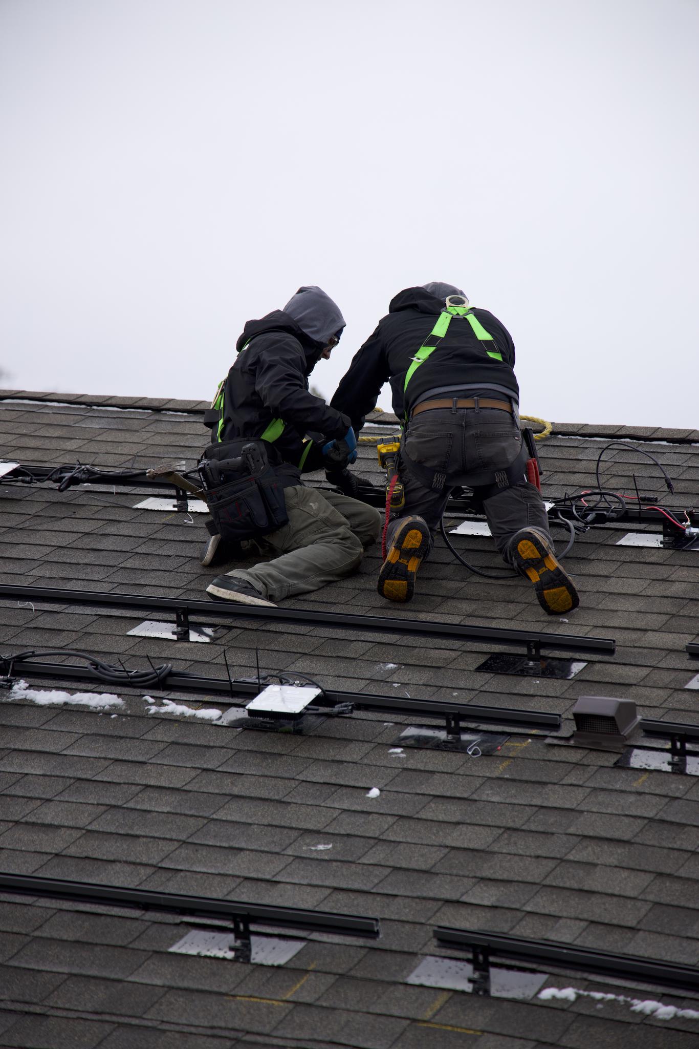 Infinity Solar crew installing panels on a rooftop in winter